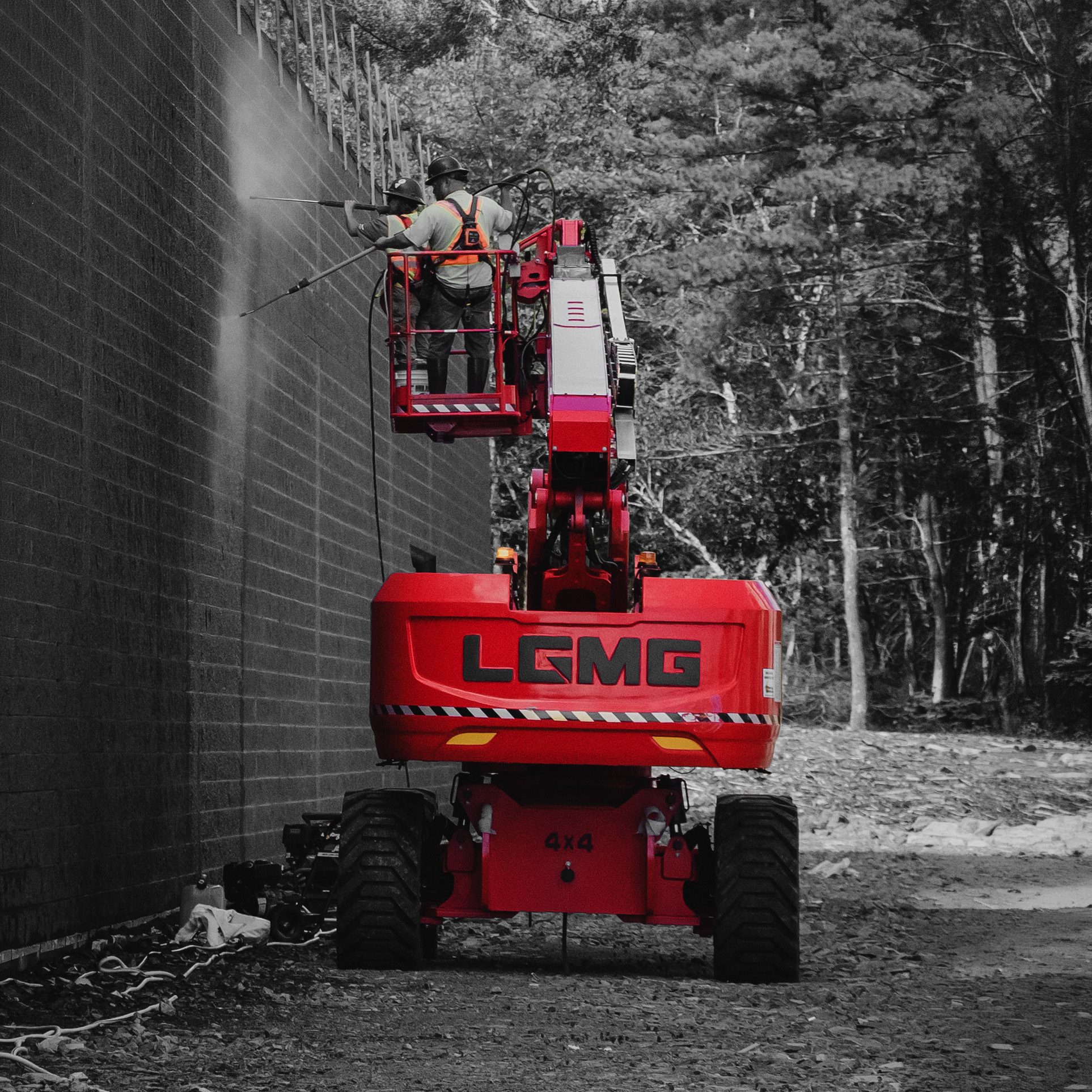 Workers in the basket of an LGMG boom lift cleaning a building wall